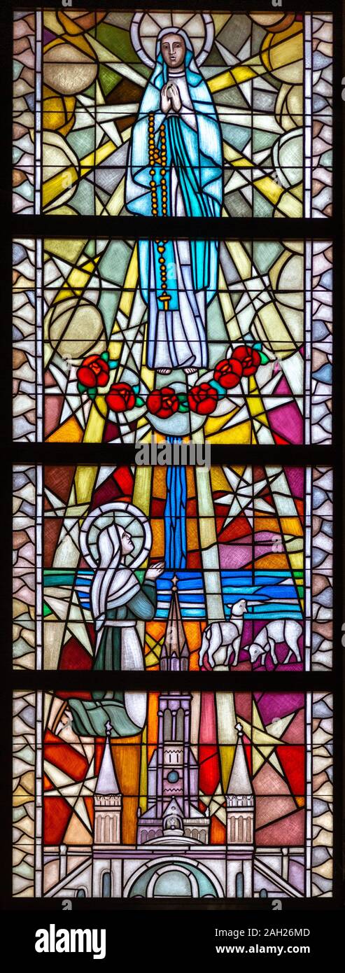 Vitrail représentant Notre Dame de Lourdes à Bernadette Soubirous dans la grotte de Massabielle. Le sanctuaire de Notre Dame de Tylicz. Banque D'Images