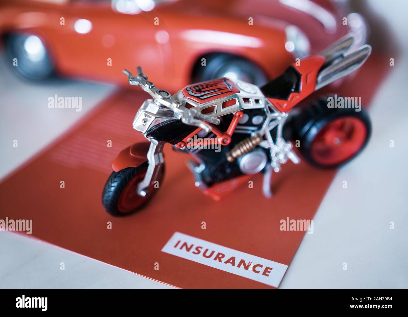 Un jouet moto garée sur une 'Assurance' flyer, à côté d'une voiture Photo  Stock - Alamy