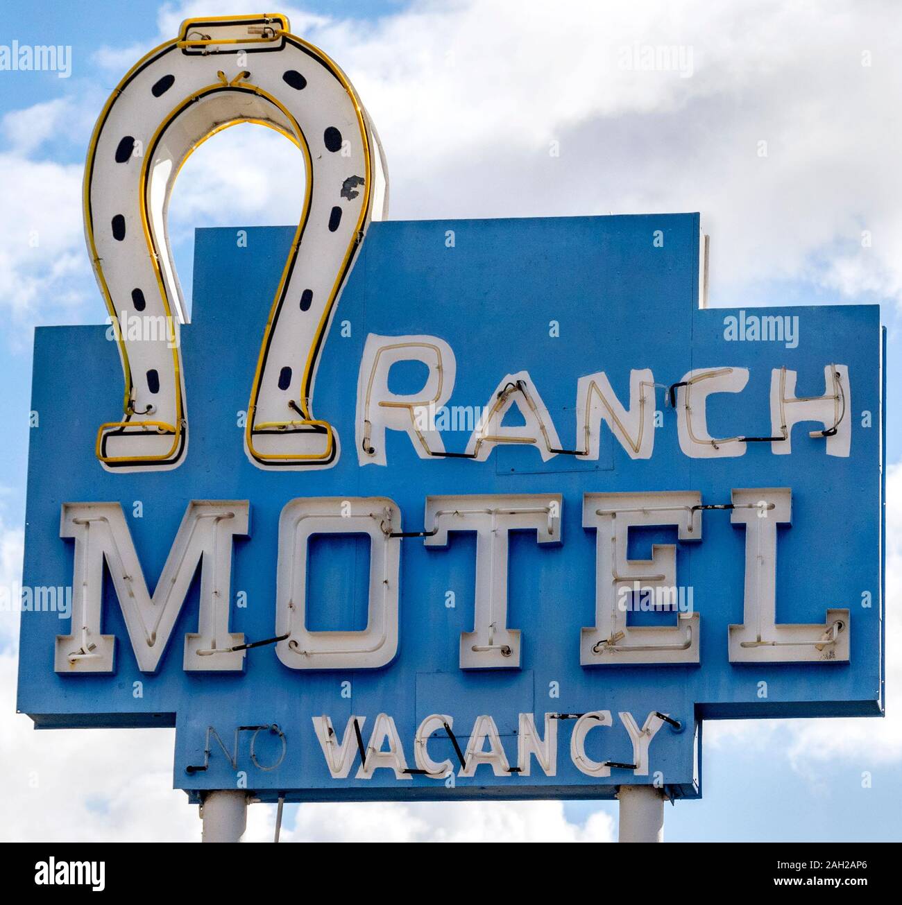 Retro 1950 motel en néon avec un fer à cheval blanc et un fond bleu. Les lettres sur le panneau bleu et blanc sont peintes à la main. Motel construit en 1956. Banque D'Images