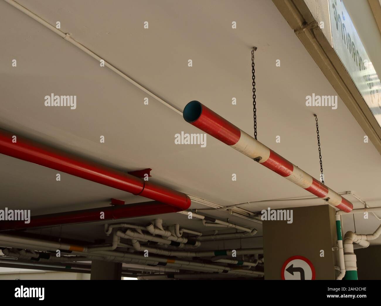 Limitation de hauteur de voiture Gros plan signe fait à partir de tuyaux de PVC peintes en rouge et blanc, suspendu au plafond par des chaînes à l'entrée du stationnement Banque D'Images