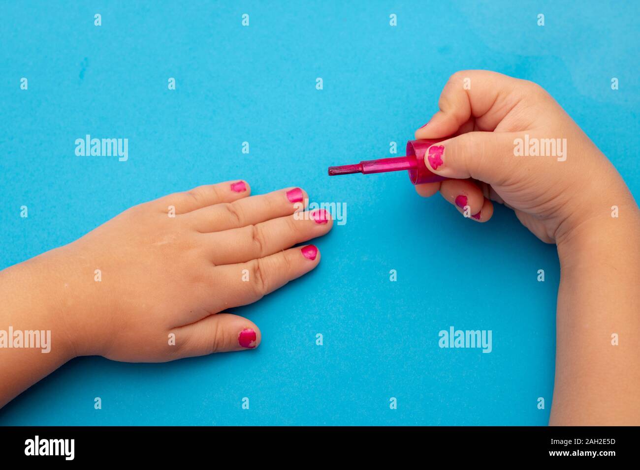 Aire de manucure. Les mains des enfants peindre les ongles avec des vernis à ongles. Manucure sur ongles rouge puéril. Banque D'Images