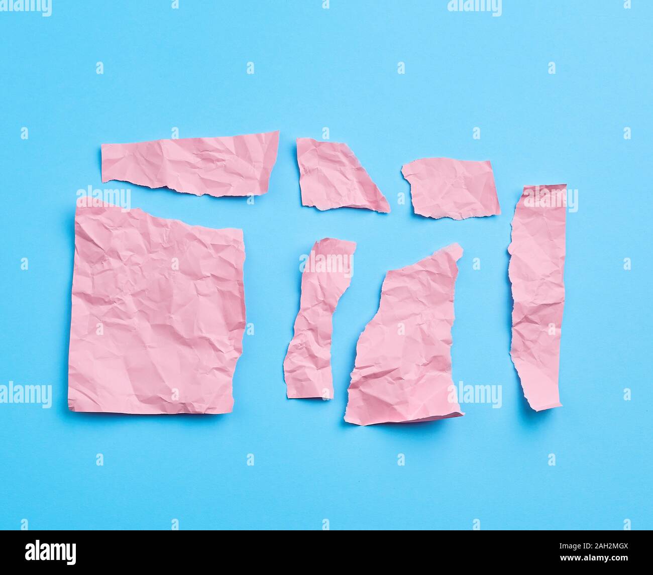 Série de couper des morceaux de papier froissé rose sur fond bleu, Close up Banque D'Images