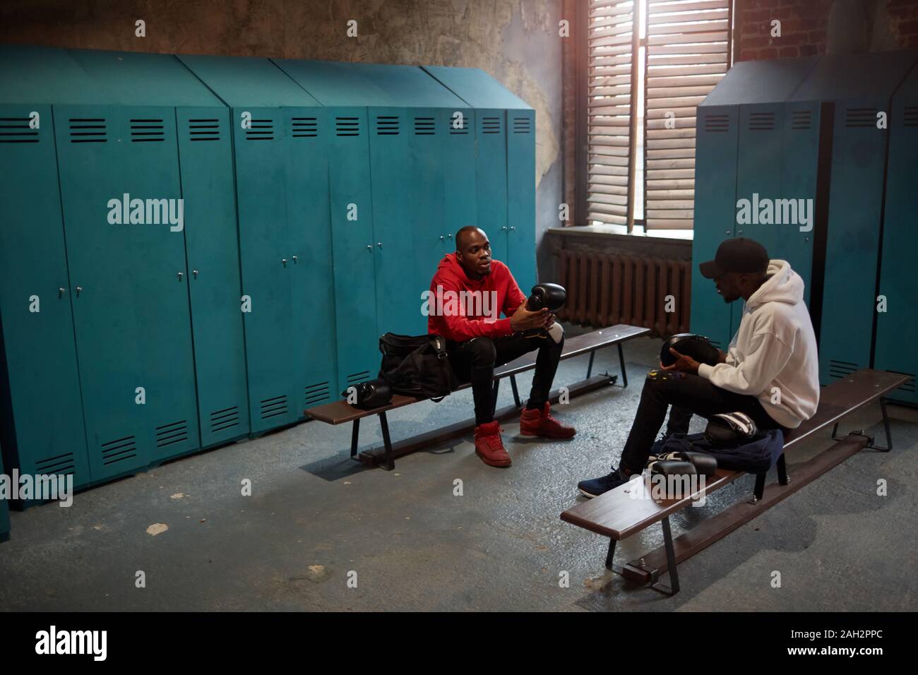 Deux boxeurs africains assis sur un banc en tenant leurs sacs de boxe et la préparation de la formation dans le vestiaire Banque D'Images
