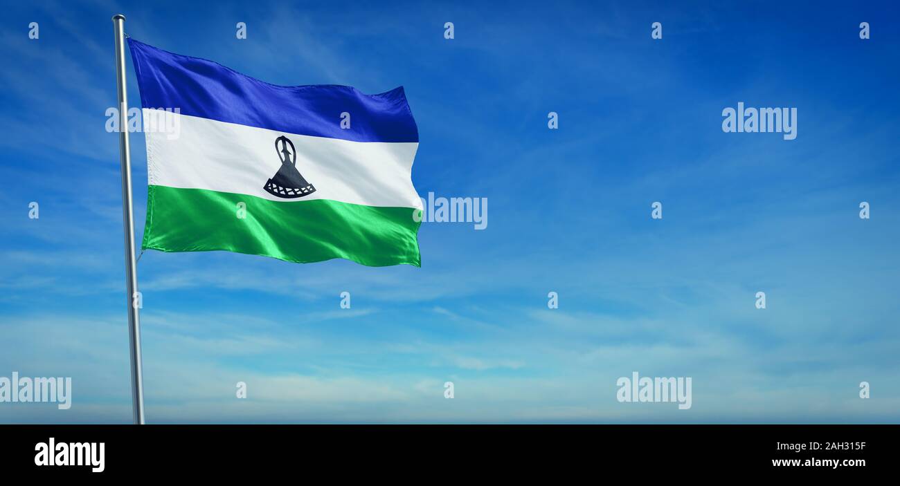 Le drapeau national du Lesotho dans le vent en face d'un ciel bleu clair Banque D'Images