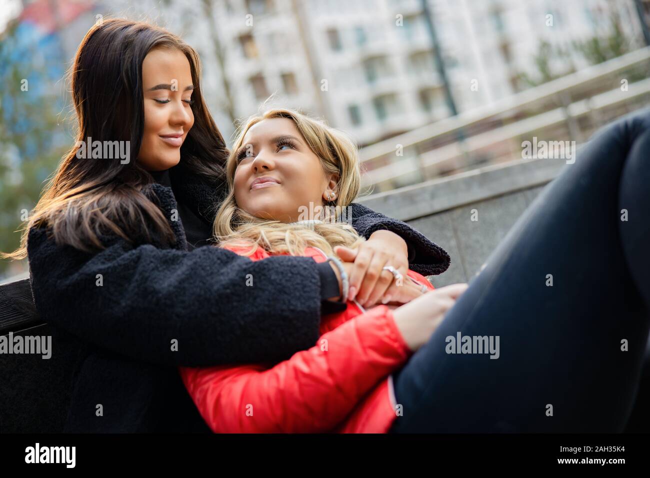 Close-up of Smiling Meilleurs amis embrassant et assis sur le sol Banque D'Images