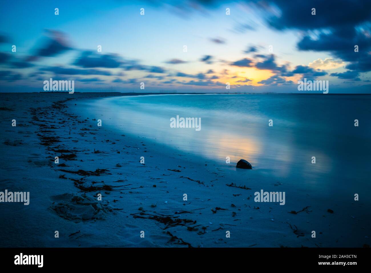 Coucher du soleil dans les Maldives avec la réflexion du soleil dans l'eau et de couleur orange et bleu des nuages dans le ciel Banque D'Images