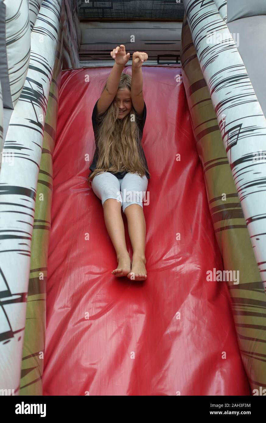Young Girl on inflatable toy in amusement park Banque D'Images