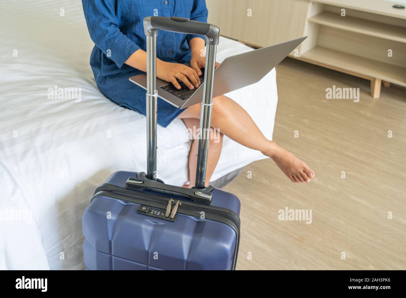 Close up of female pigiste à l'aide d'ordinateur portable à côté de valise Banque D'Images