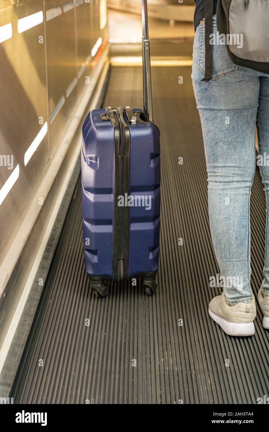 Jeune voyageur holding hand-carry sur escalator valise à l'aéroport. Banque D'Images