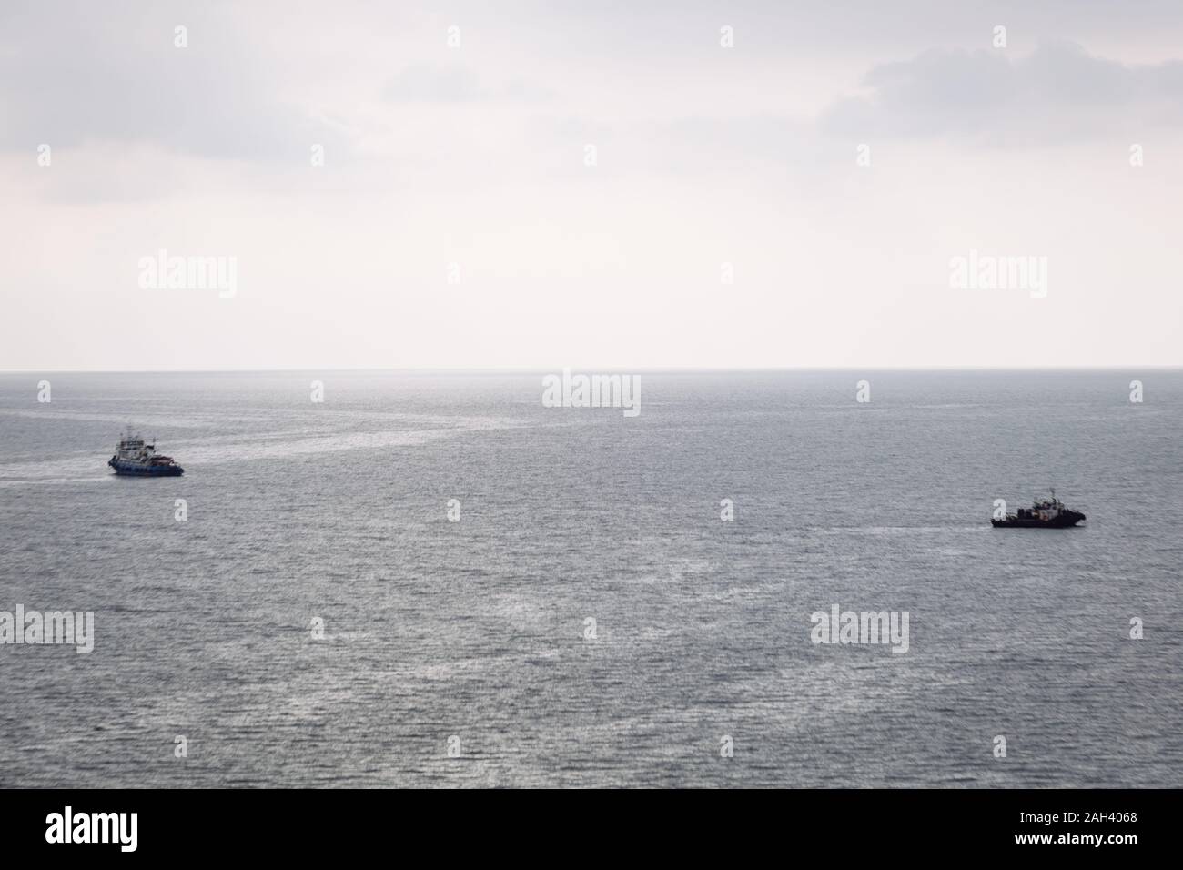 Deux bateaux naviguent dans des directions différentes sur la mer sur un jour nuageux Banque D'Images