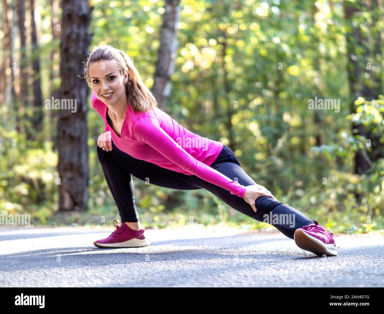Smiling woman étirer muscles au parc. L'exercice athlétique utdoor. Banque D'Images