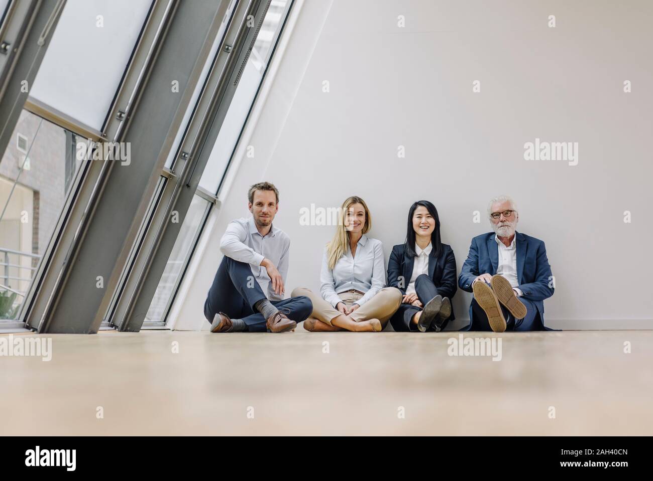 Portrait of smiling business people assis sur le plancher d'office Banque D'Images