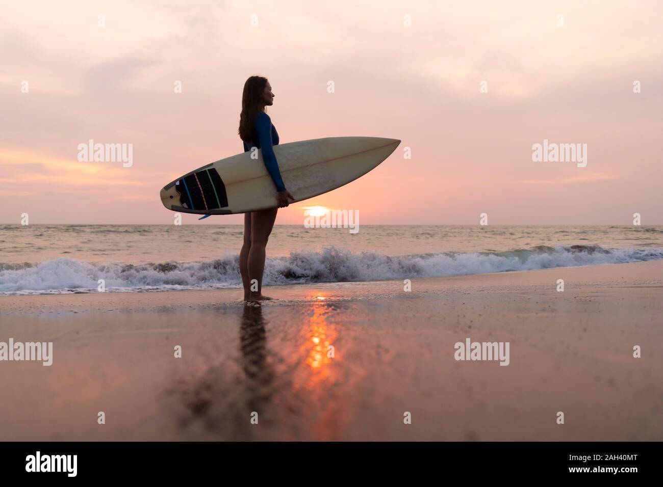 Jeune femme avec une planche de surf à la plage, plage de Kedungu, Bali, Indonésie Banque D'Images
