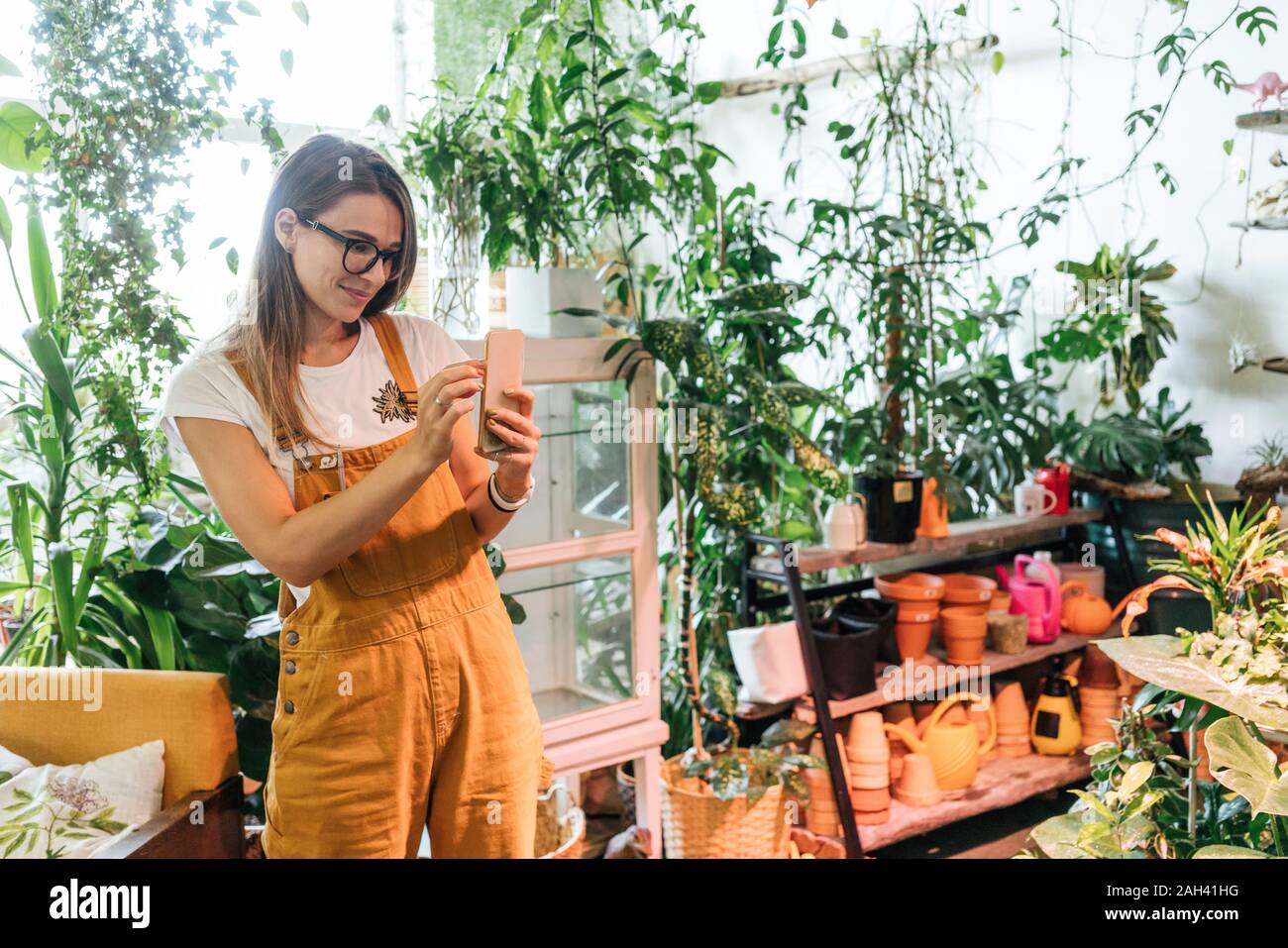 Young woman taking photo smartphone dans un petit magasin de jardinage Banque D'Images