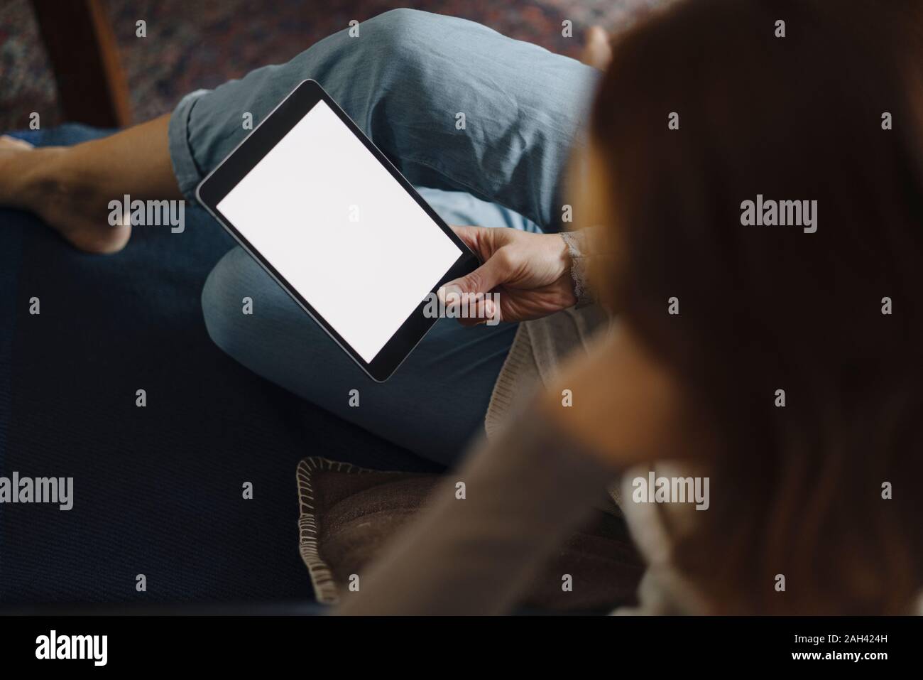 Woman sitting on couch, using digital tablet Banque D'Images