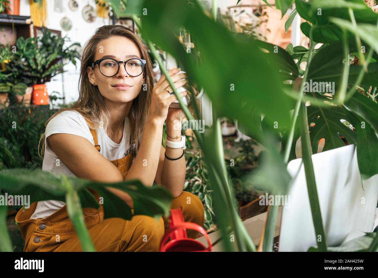 Portrait d'une jeune femme ayant une pause café dans une petite boutique de jardinage Banque D'Images