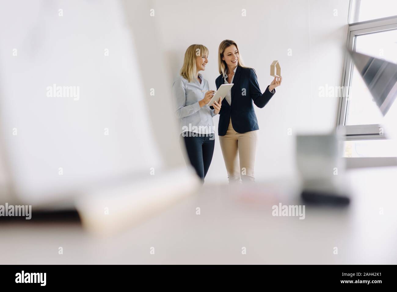 Deux jeunes femmes avec tablet et house model in office Banque D'Images