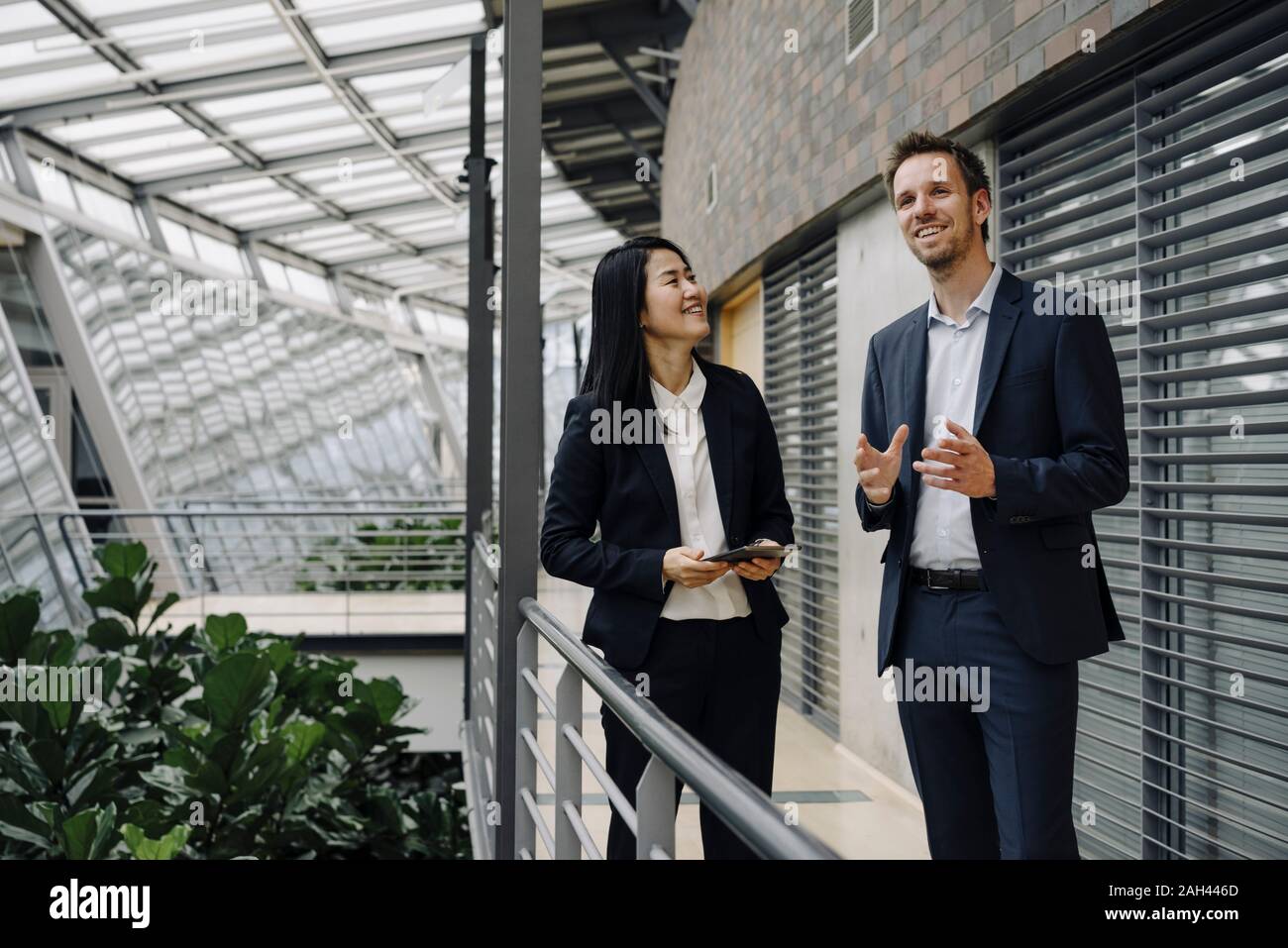 Businessman and businesswoman with tablet talking in modern office building Banque D'Images