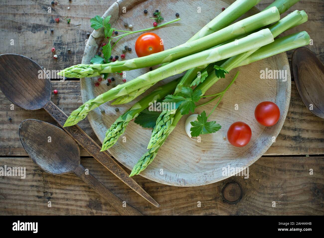 Deux cuillères en bois et plateau avec asperges fraîches, les tomates cerises, le persil et le poivre Banque D'Images