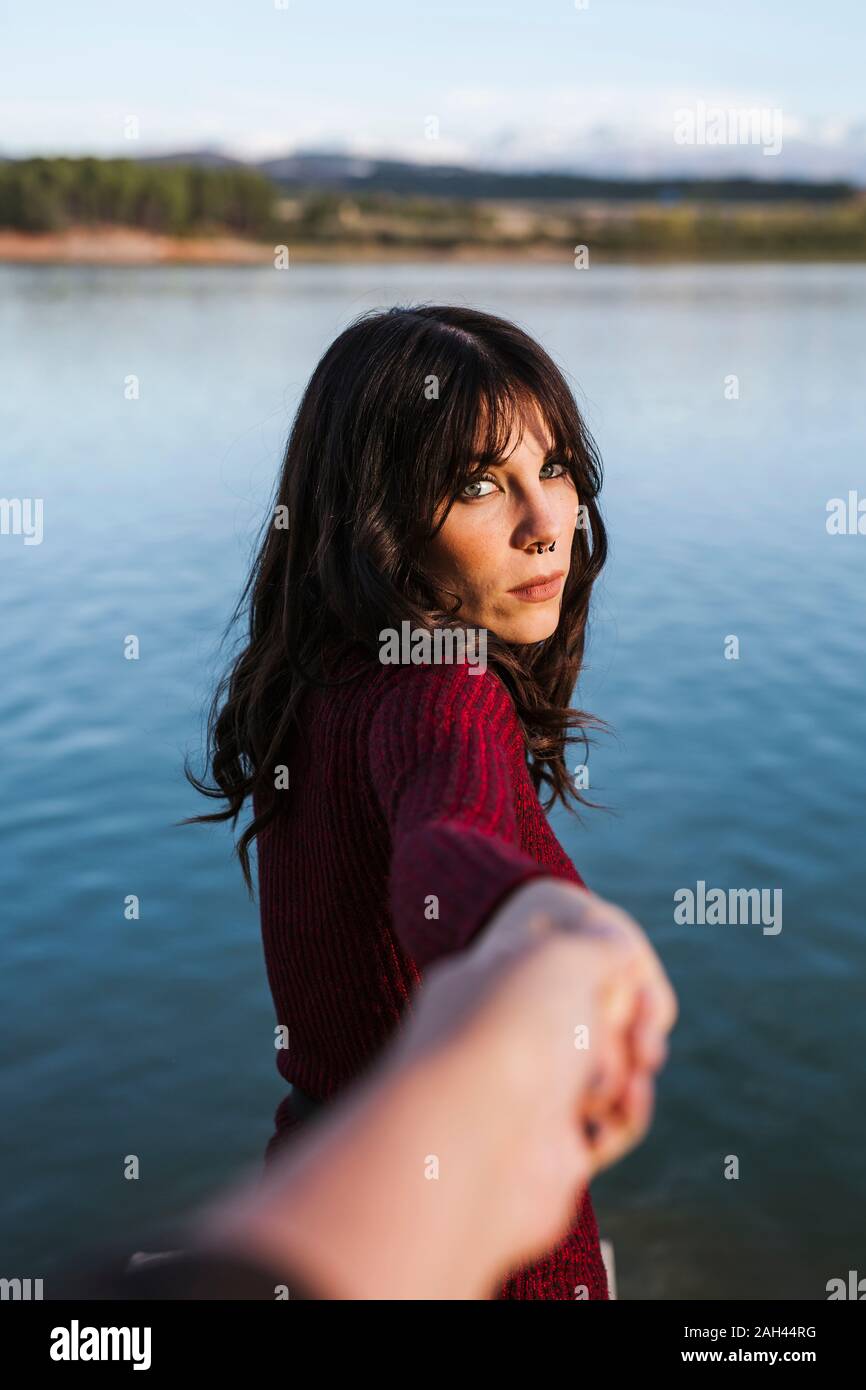 Jeune femme tenant la main d'un homme, debout au bord du lac Banque D'Images