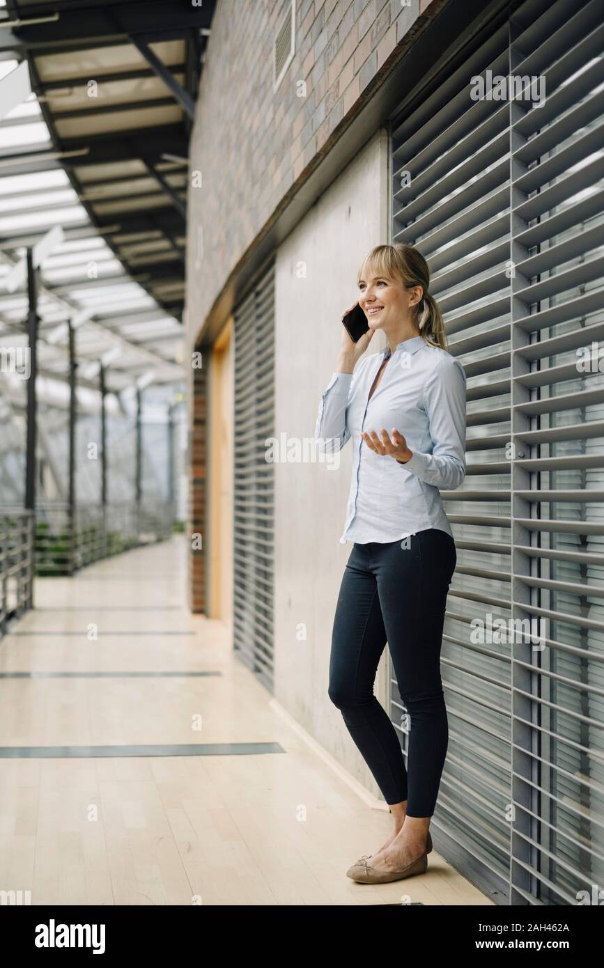 Smiling young businesswoman au téléphone dans un immeuble de bureaux modernes Banque D'Images