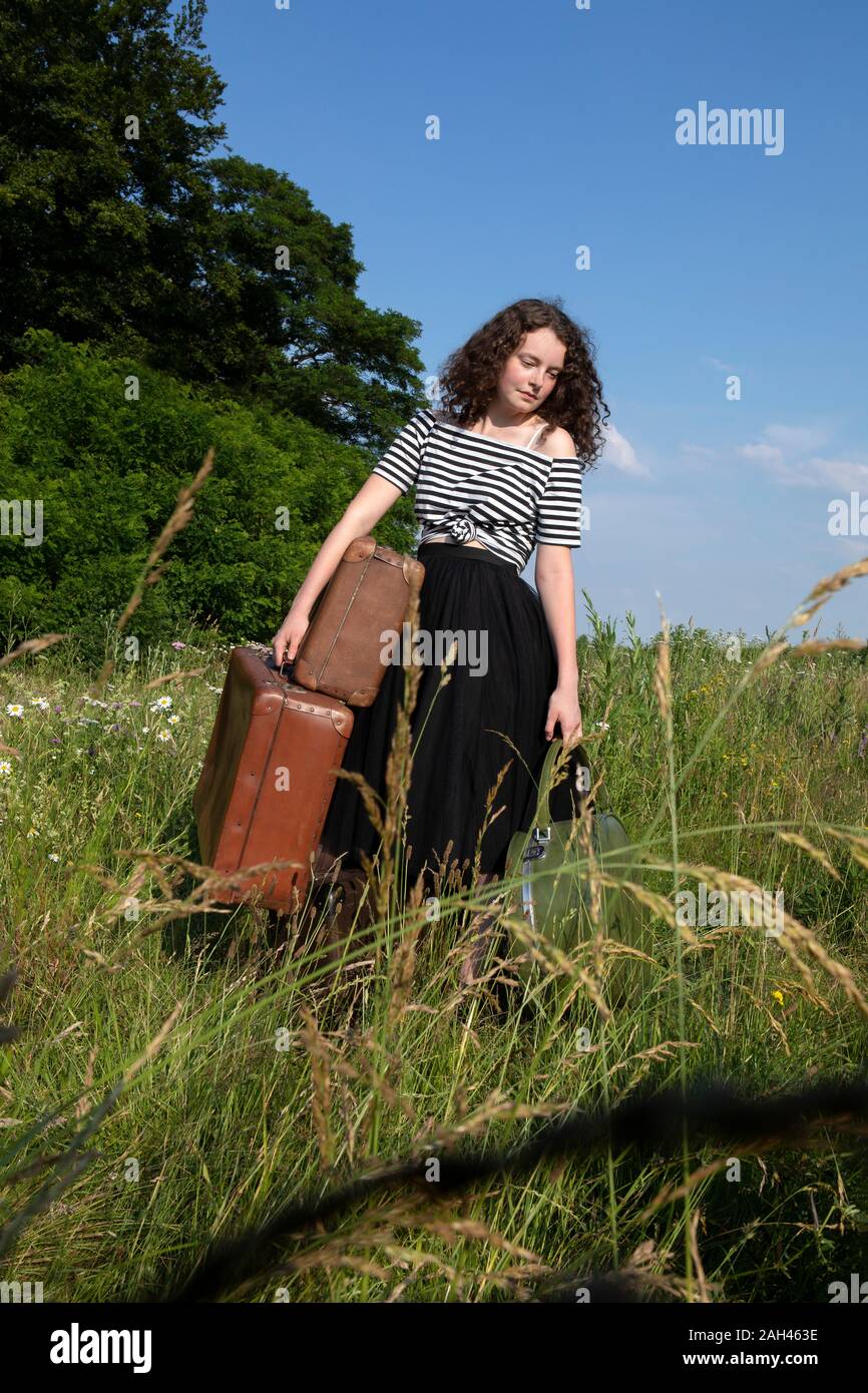 Portrait de jeune femme sur une prairie avec de nombreuses valises Banque D'Images