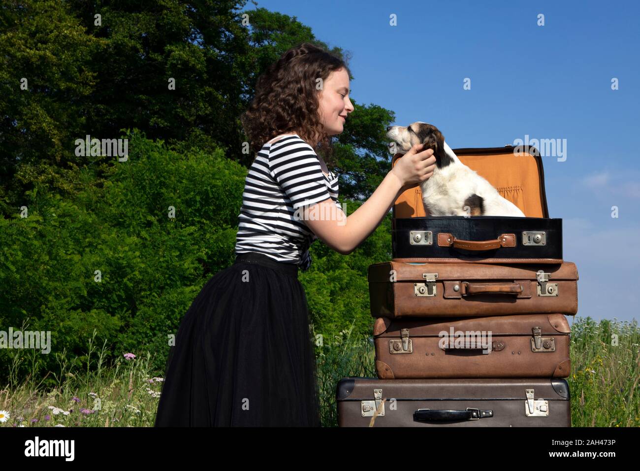 Jeune femme de câlins petit chien assis dans suitcase Banque D'Images