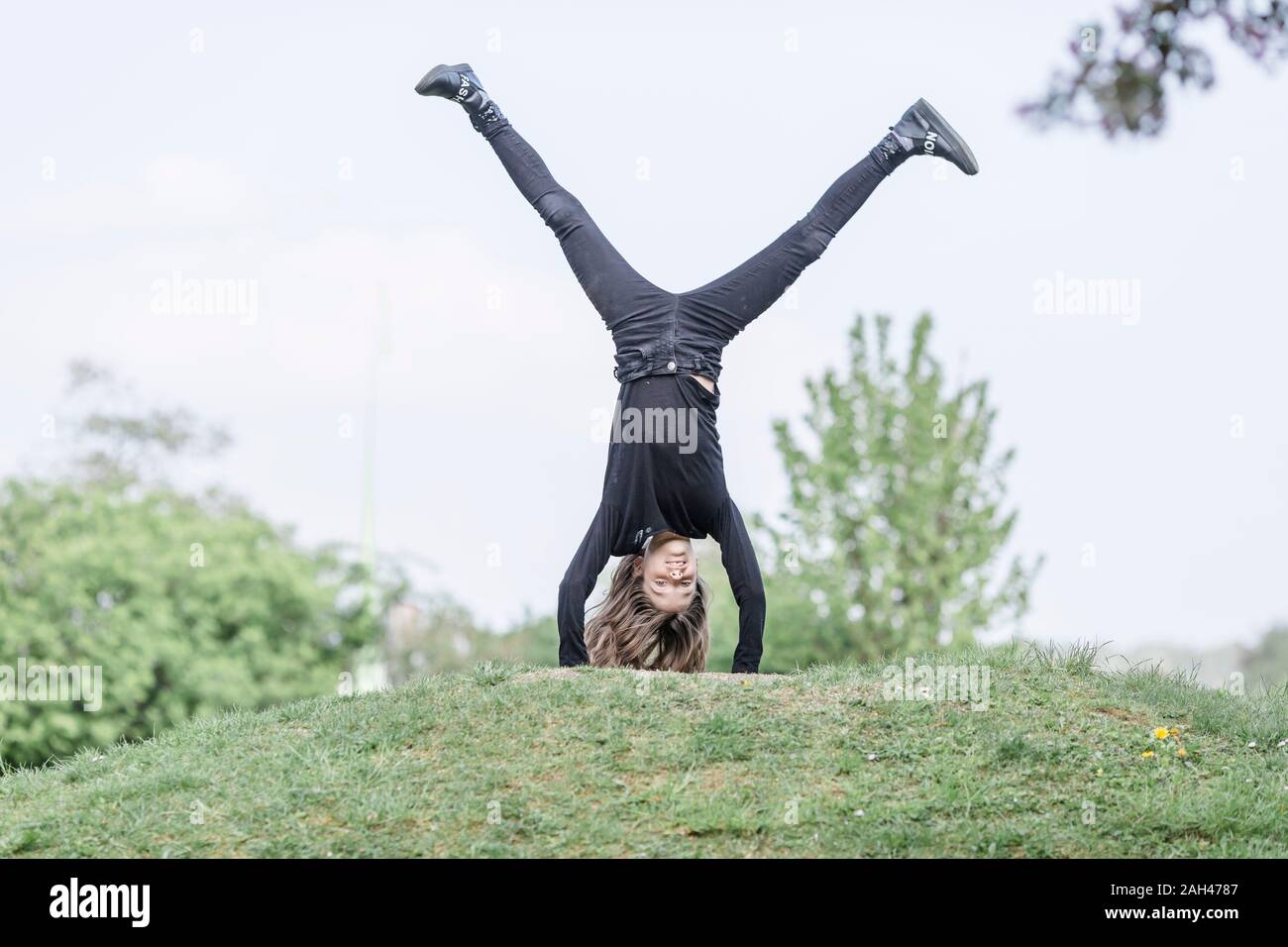 Girl doing a handstand on a meadow Banque D'Images