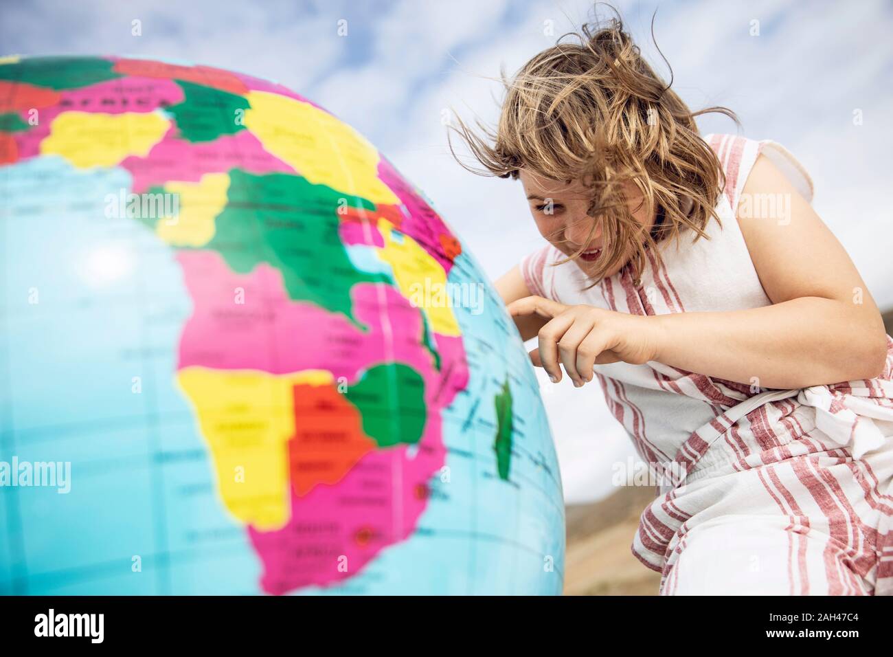 Little girl pointing sur inflatable globe Banque D'Images