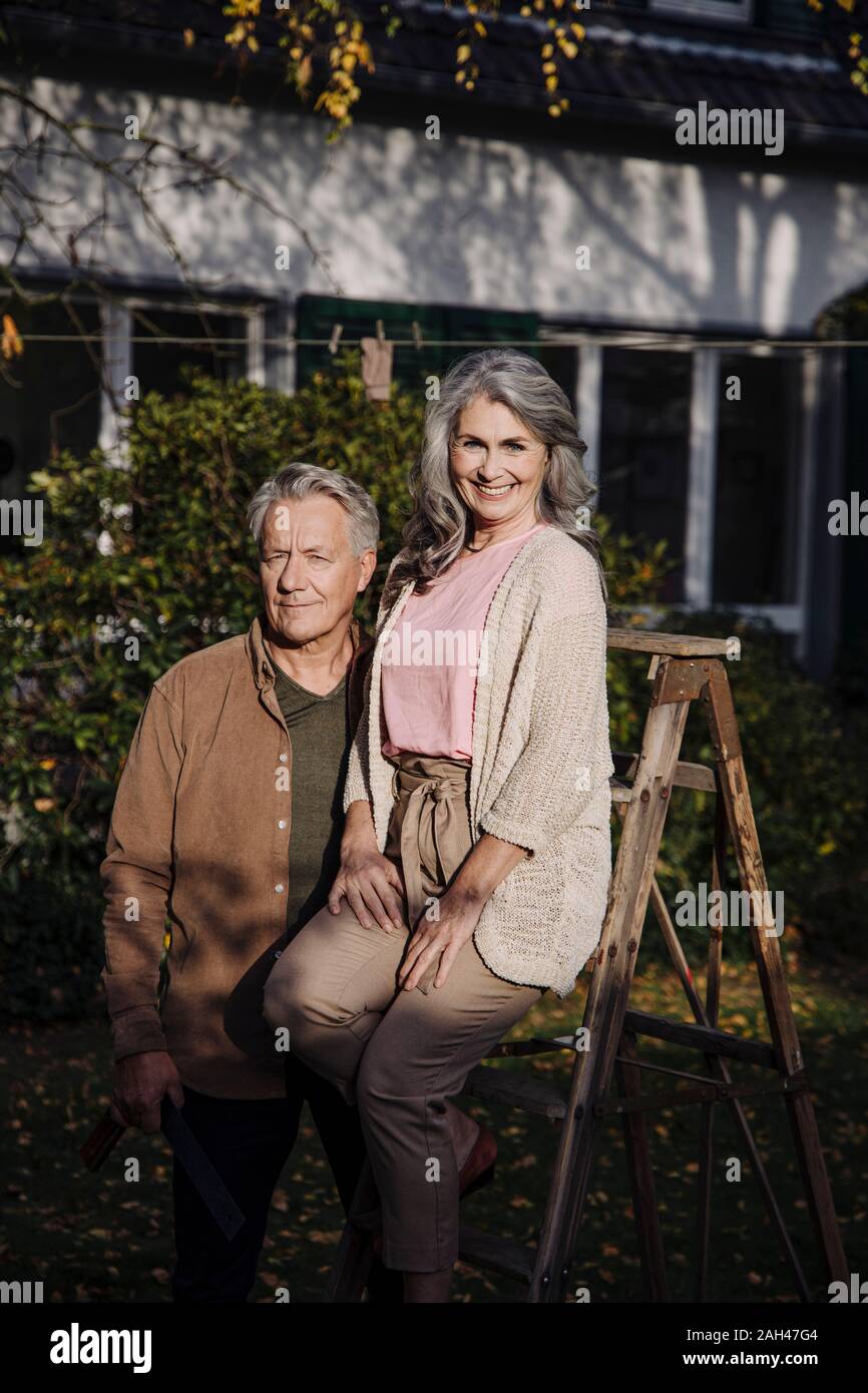 Couple avec une échelle dans le jardin de leur maison Banque D'Images