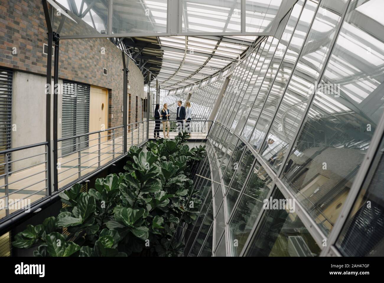 Les gens d'affaires debout sur une passerelle en immeuble de bureaux modernes Banque D'Images
