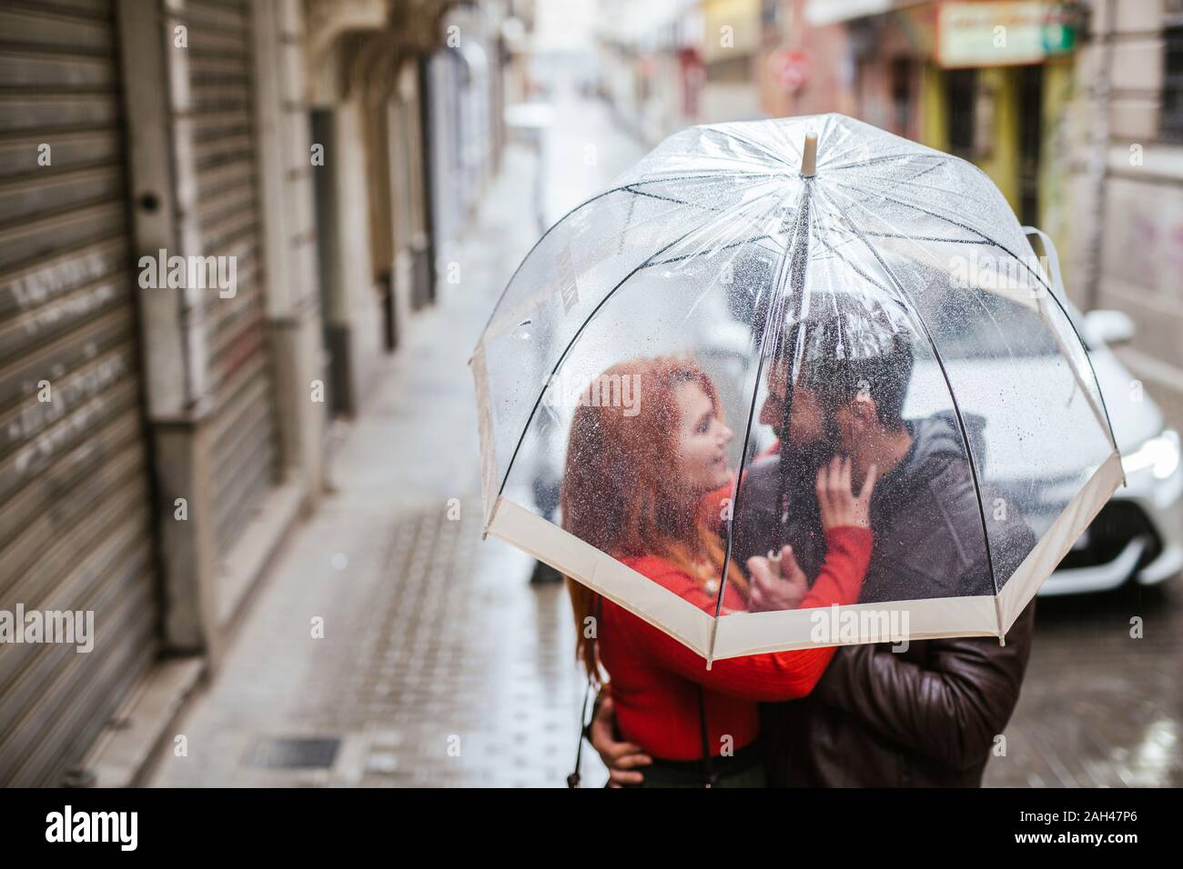 Couple in love sous parapluie transparent dans la ville Banque D'Images