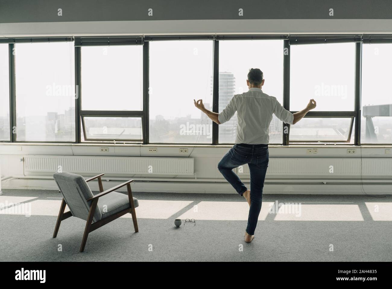 Man practicing yoga in empty office Banque D'Images