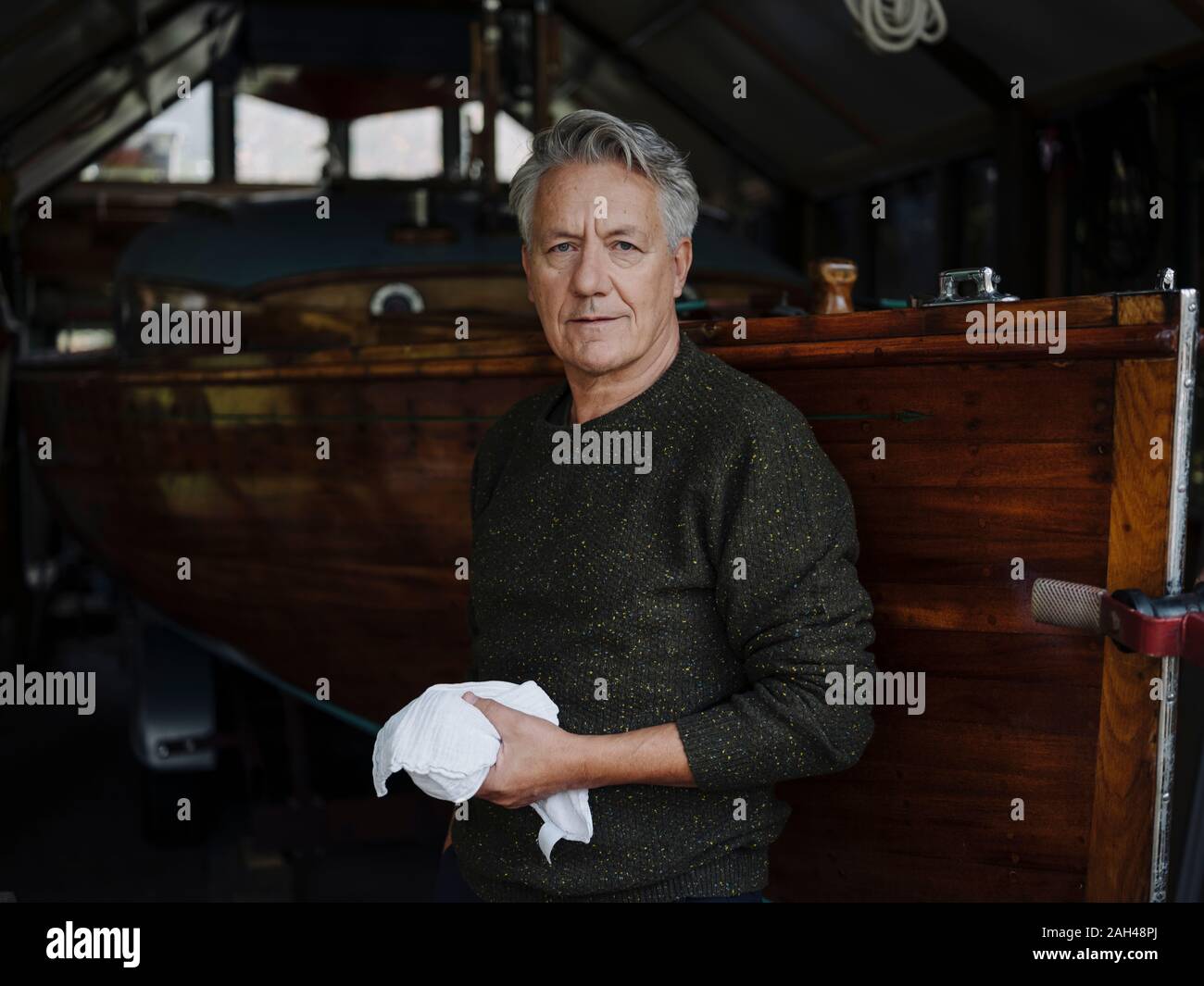 Portrait of a senior man avec chiffon en bateau en bois dans un hangar à bateaux Banque D'Images