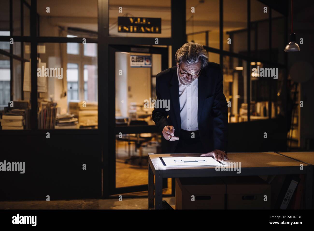 Senior businessman looking at shining tablet in office Banque D'Images