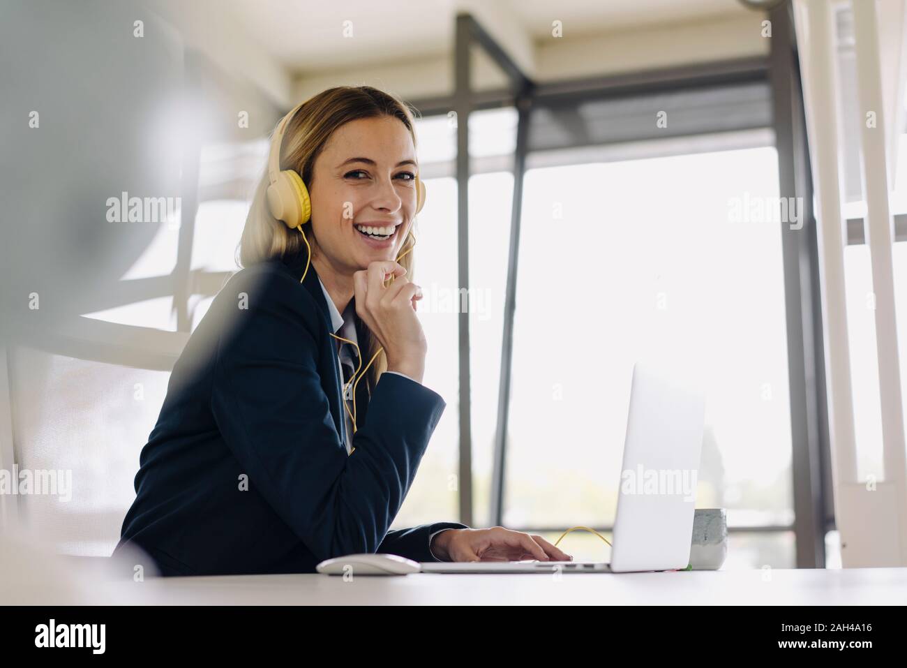 Portrait of happy young businesswoman au casque et le laptop at desk in office Banque D'Images