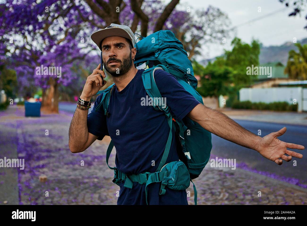 Backpacker standing on a street en utilisant son smartphone Banque D'Images