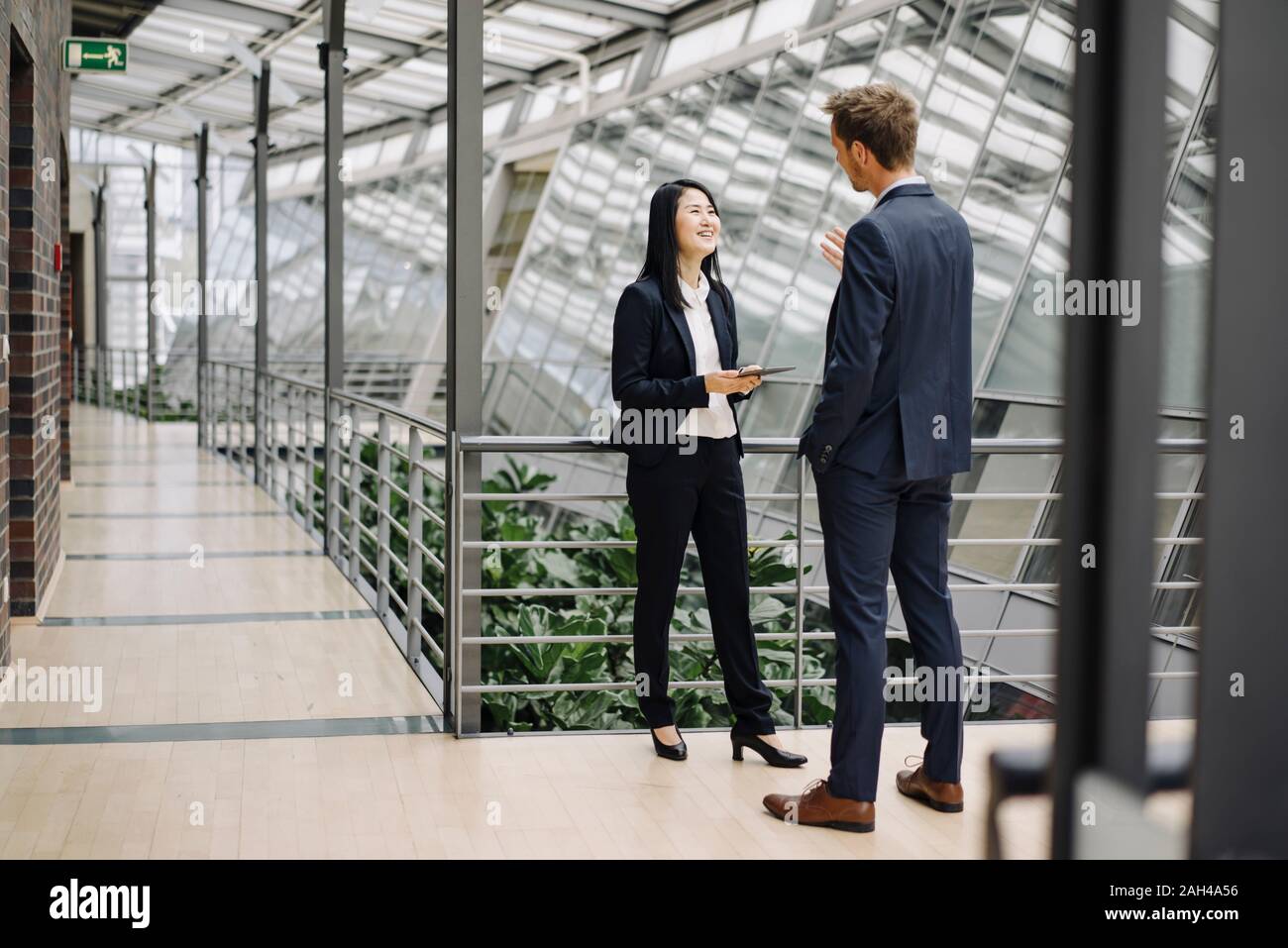 Businessman and businesswoman with tablet talking in modern office building Banque D'Images