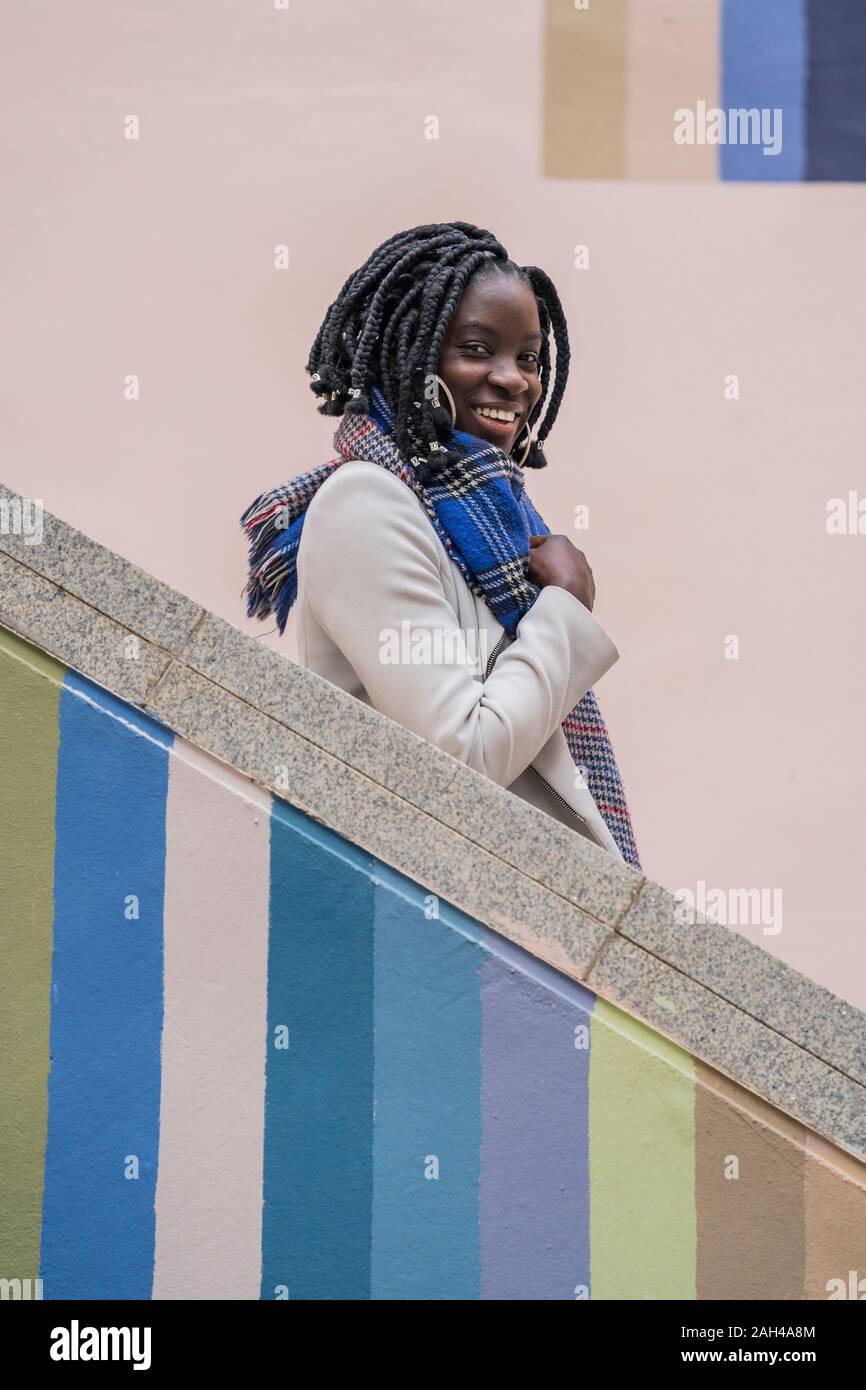 Portrait of happy young woman with black tresses sur escalier coloré Banque D'Images Portrait of happy young woman with black tresses sur escalier coloré Banque D'Images