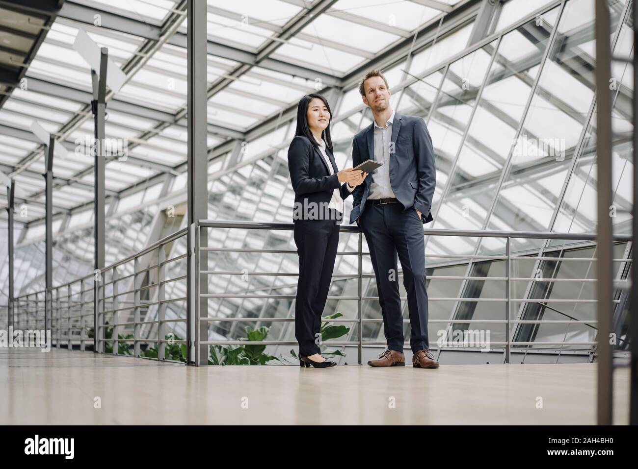 Businessman and businesswoman with tablet debout dans immeuble de bureaux modernes Banque D'Images