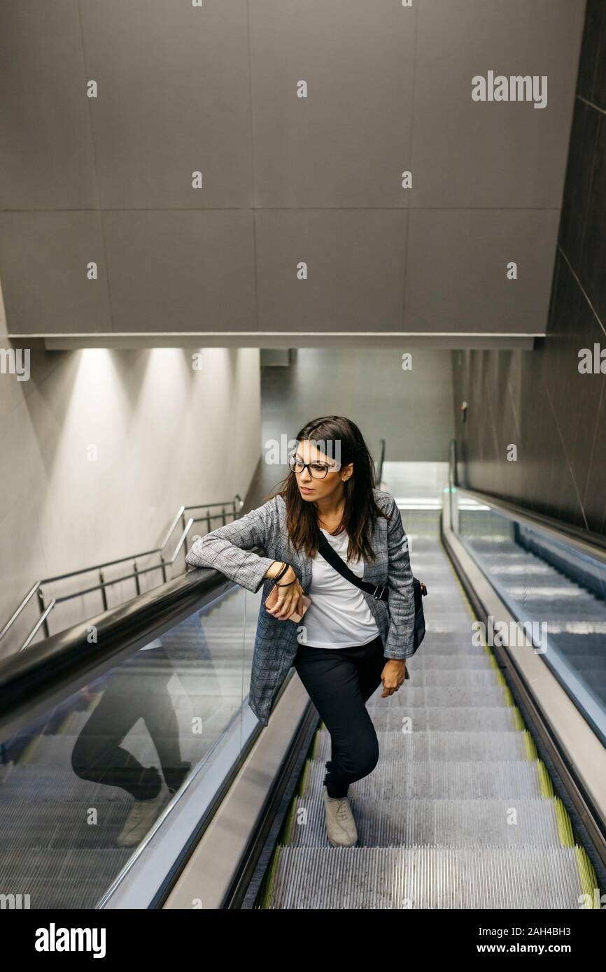 Businesswoman standing on escalator d'une station de métro Banque D'Images