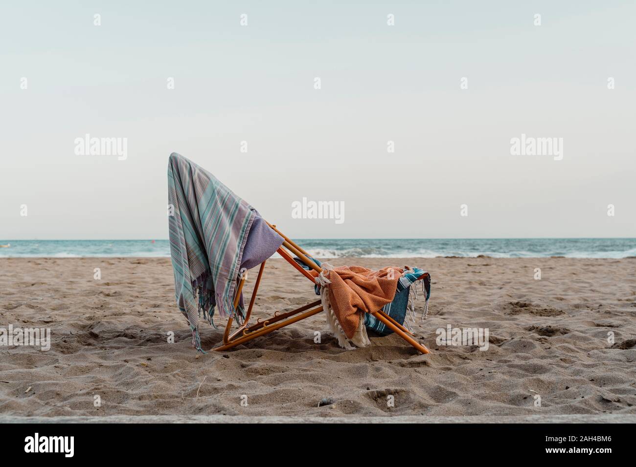 Espagne, Province de Barcelone, el Garraf, des serviettes de plage accroché sur une chaise à gauche sur la plage sableux côtiers au crépuscule Banque D'Images