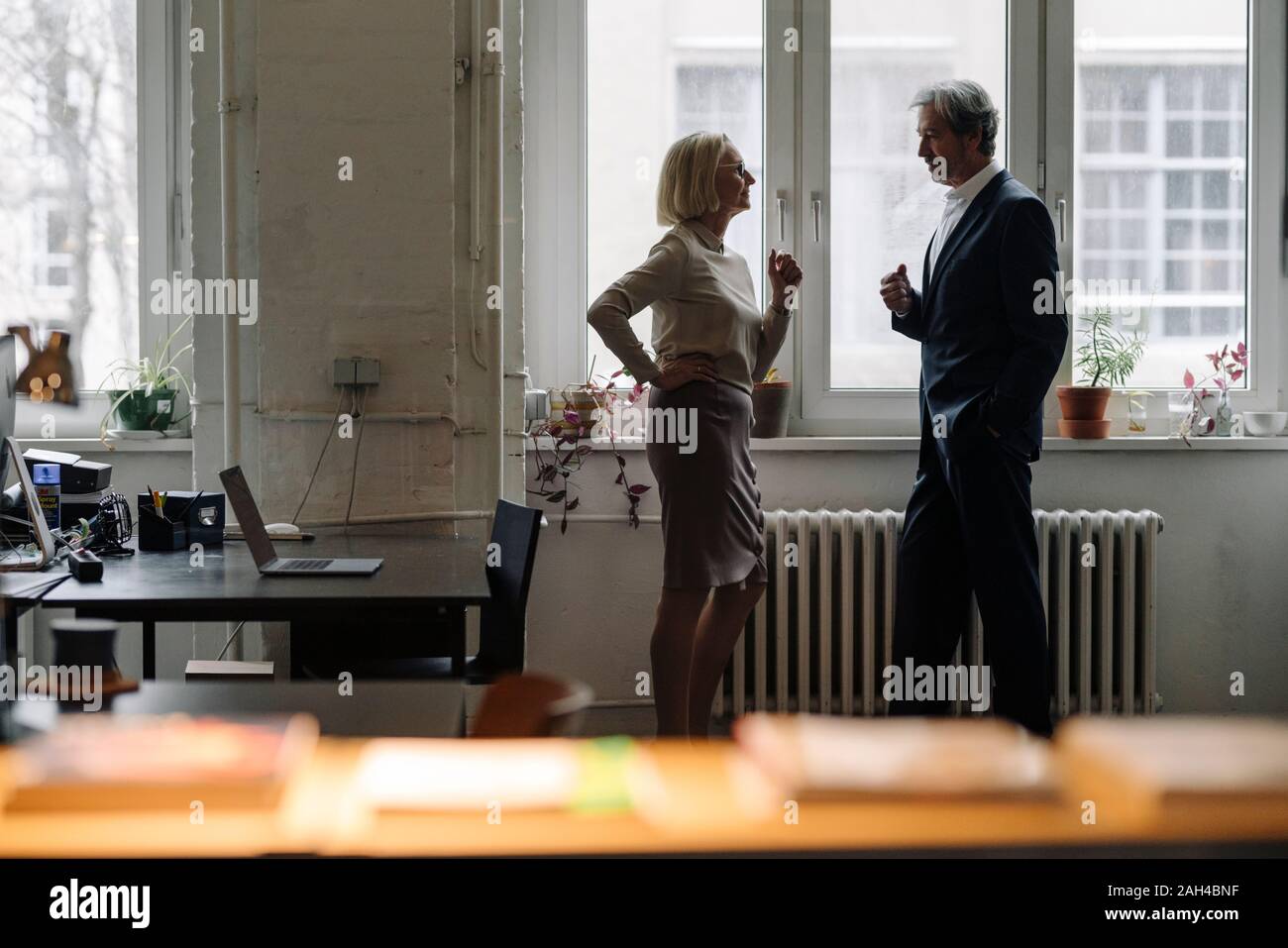 Businessman and businesswoman talking in office à la fenêtre Banque D'Images