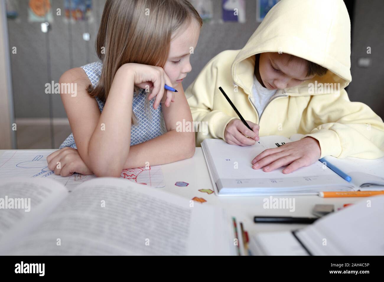 Frère et soeur assis à table à la maison à faire leurs devoirs ensemble Banque D'Images