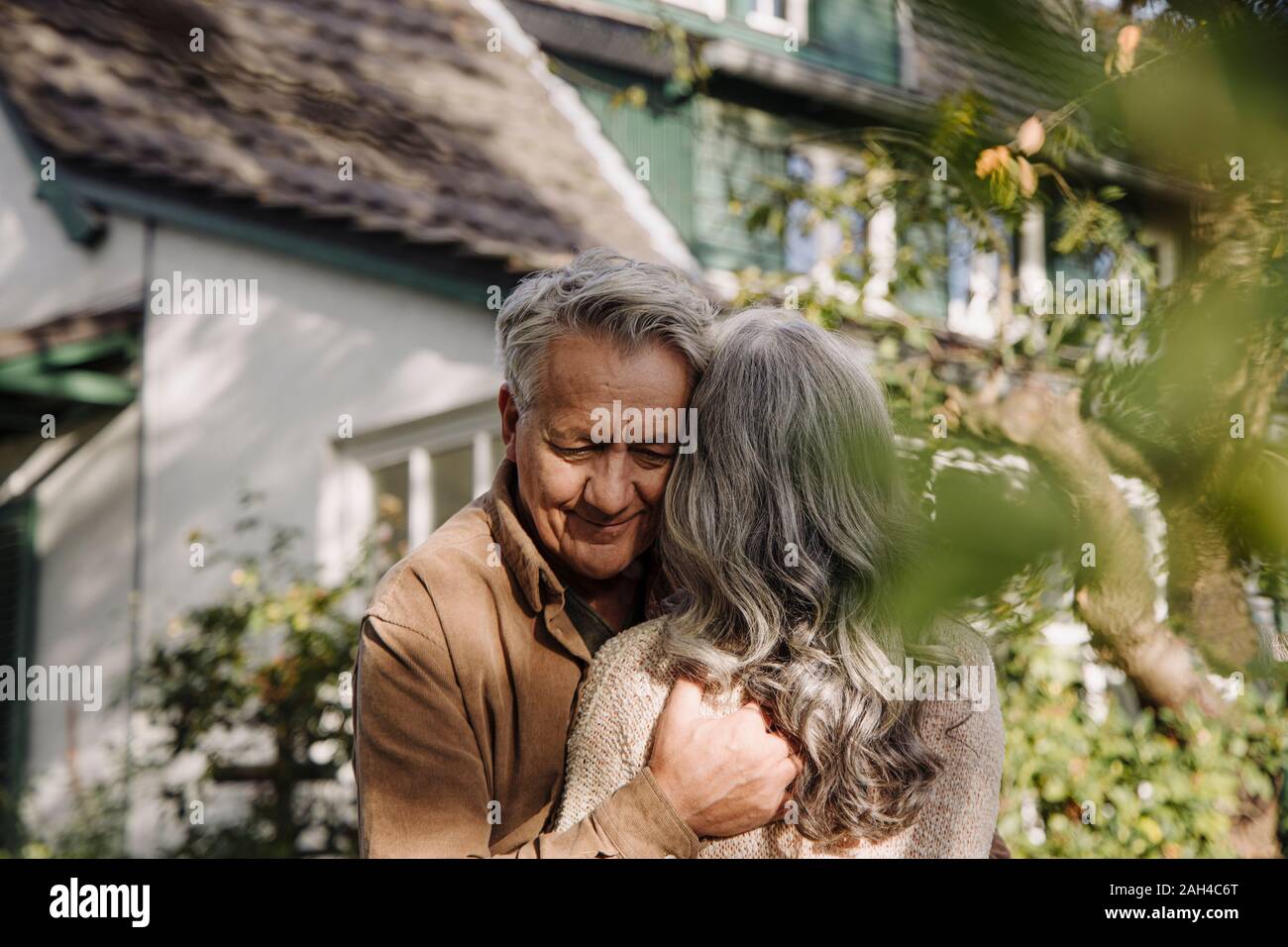 Man hugging son épouse dans le jardin de leur maison à l'automne Banque D'Images
