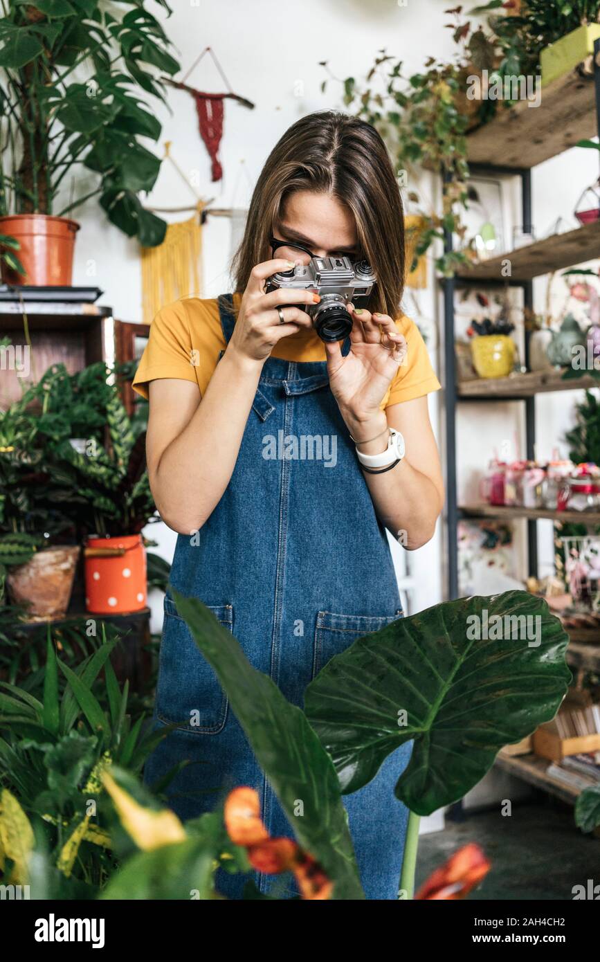 Young woman taking photos de plantes dans un petit magasin de jardinage Banque D'Images