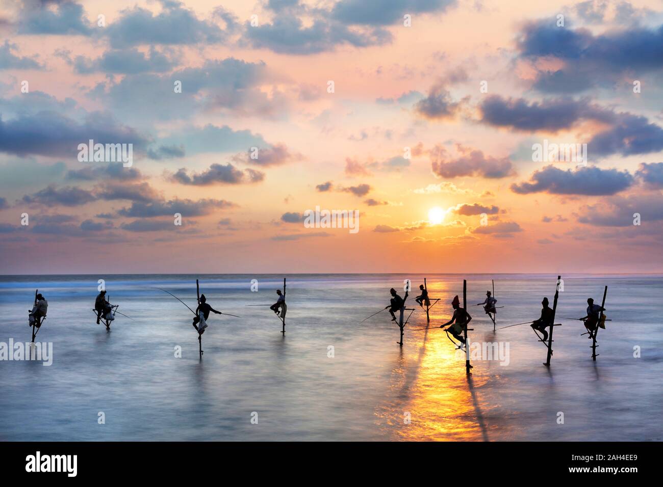 Les pêcheurs sur les échasses en silhouette au coucher du soleil au Sri Lanka. Banque D'Images