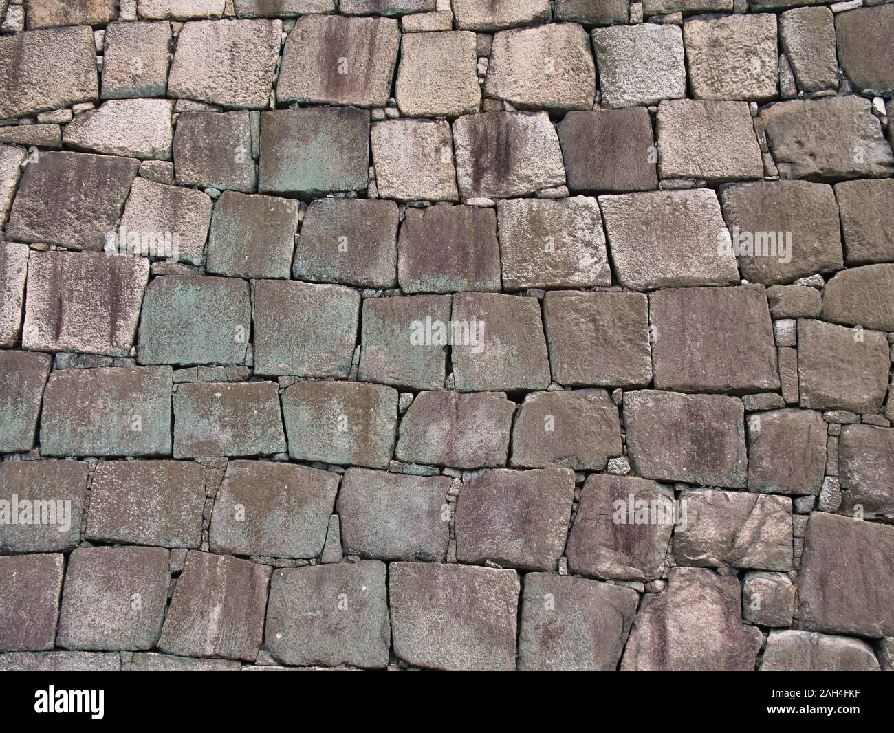 Parpaings de roche naturelle dans un mur avec des couleurs vert et lilas causée par les algues et la croissance des lichens - convient pour un arrière-plan graphique. Banque D'Images