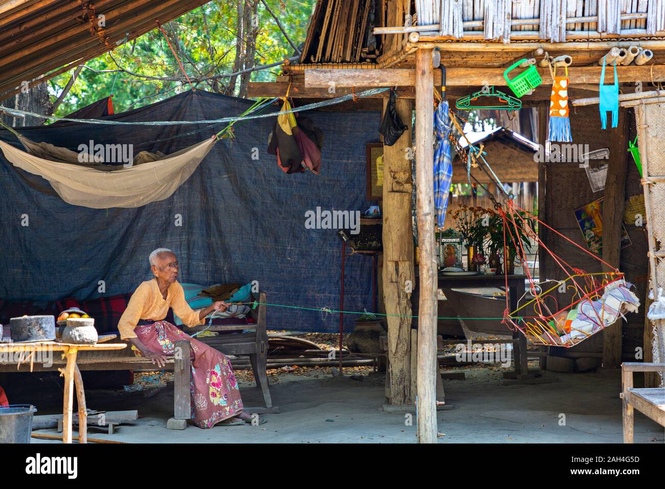 Femme âgée balance le berceau de bébé, à Bagan, Myanmar Banque D'Images