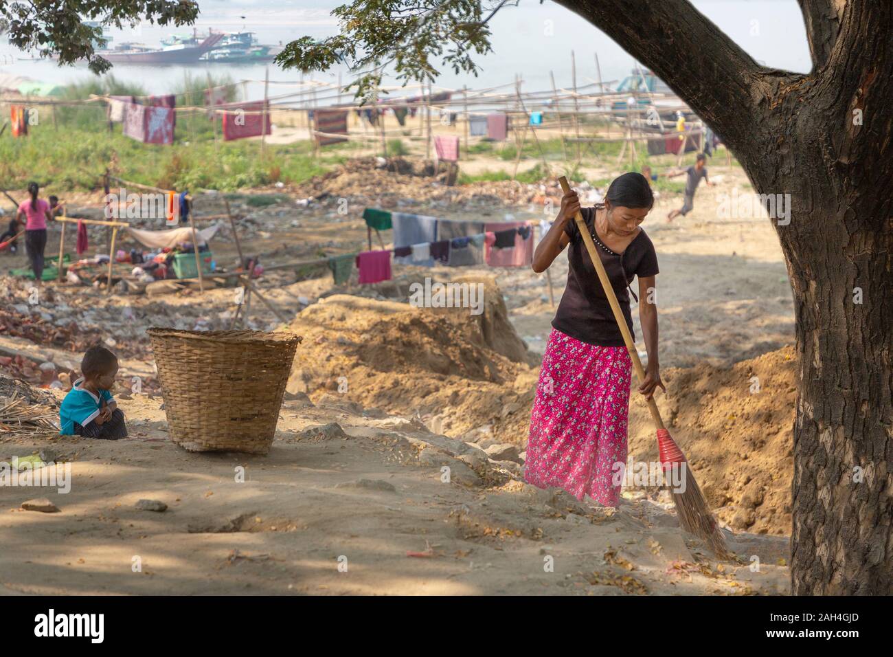 Woman sweeping local dans la colonie près de la rivière Irrawaddy, à Mandalay, Myanmar Banque D'Images